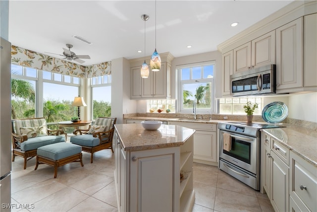 kitchen featuring ceiling fan, hanging light fixtures, sink, a kitchen island, and stainless steel appliances