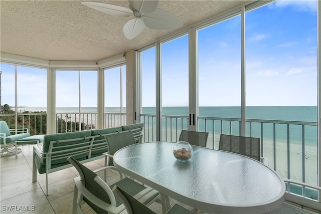 sunroom featuring ceiling fan and a water view