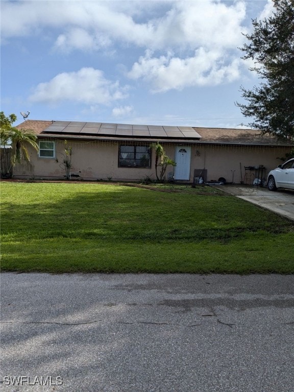 ranch-style home with solar panels and a front yard