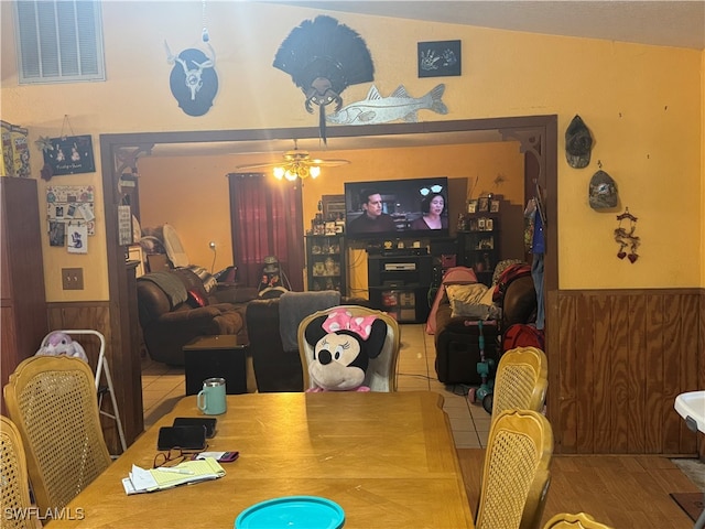 dining room with wood walls, tile patterned flooring, and ceiling fan