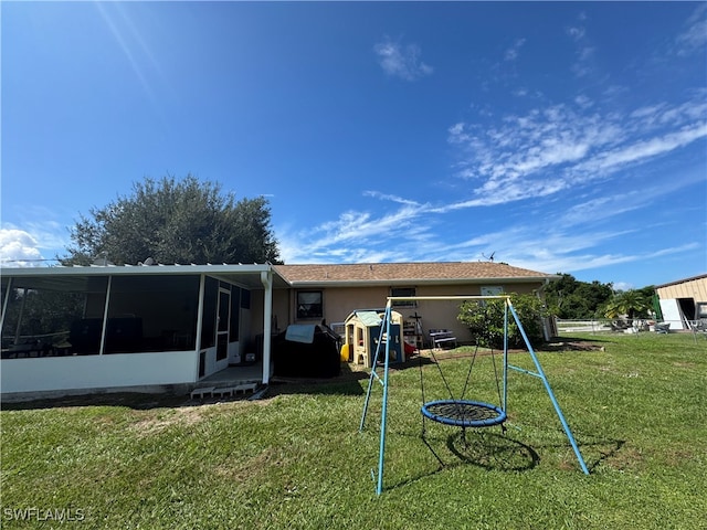 rear view of house featuring a yard and a sunroom