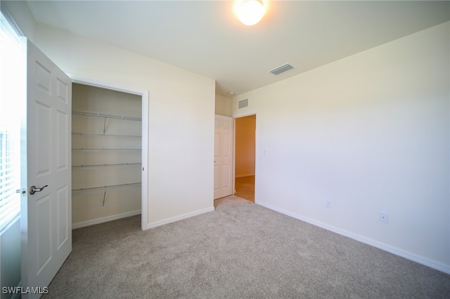 unfurnished bedroom with multiple windows, light colored carpet, and a closet