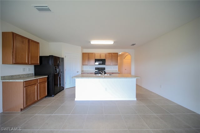 kitchen featuring black appliances, a center island with sink, light tile patterned floors, and sink