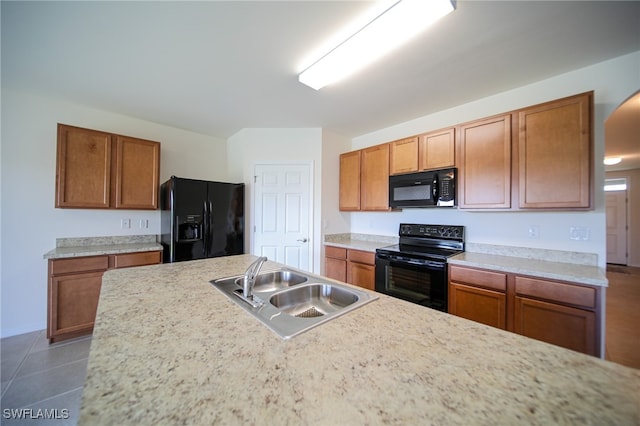 kitchen with dark tile patterned floors, black appliances, and sink