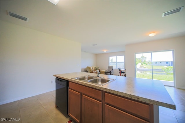 kitchen featuring light tile patterned floors, dishwasher, sink, and an island with sink