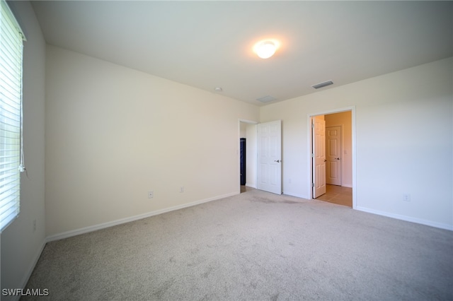 unfurnished bedroom featuring connected bathroom and light colored carpet