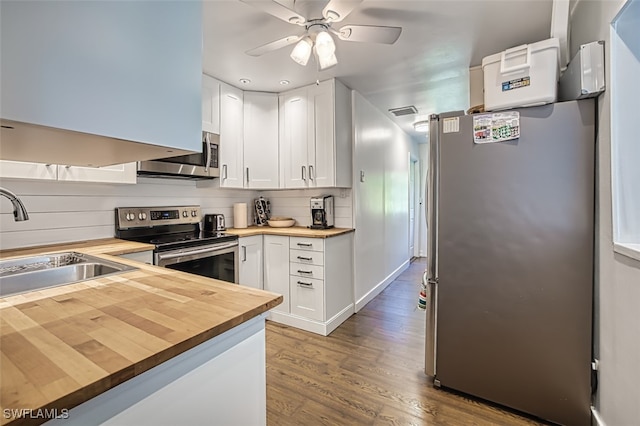 kitchen with wood counters, stainless steel appliances, hardwood / wood-style flooring, white cabinetry, and ceiling fan