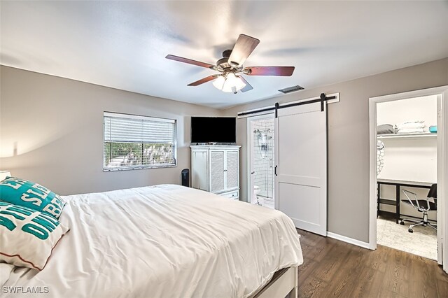 bedroom featuring a barn door, ceiling fan, and dark wood-type flooring