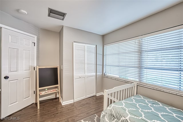 bedroom with dark wood-type flooring and a closet