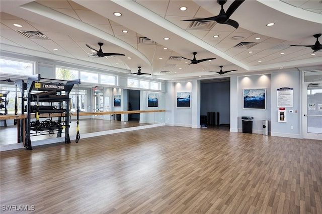 workout room featuring wood-type flooring, a towering ceiling, and a drop ceiling