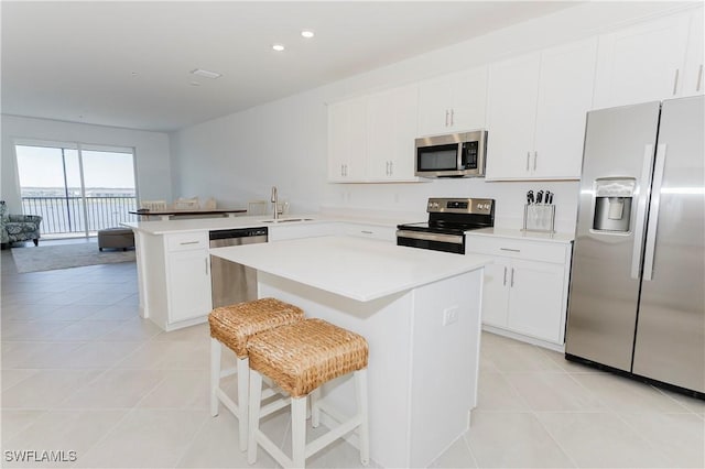 kitchen featuring appliances with stainless steel finishes, white cabinets, a kitchen island, and sink