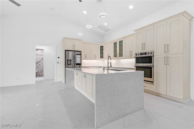 kitchen with pendant lighting, sink, ceiling fan, appliances with stainless steel finishes, and a center island with sink