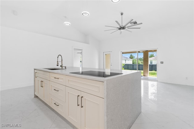 kitchen featuring ceiling fan, lofted ceiling, sink, an island with sink, and black electric stovetop