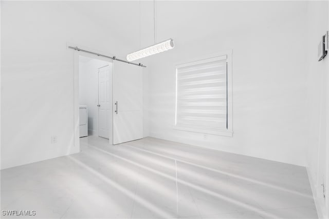 empty room featuring washer / clothes dryer and a barn door