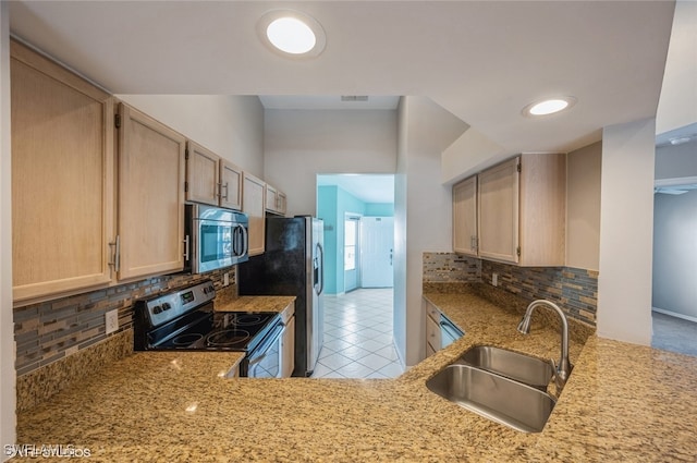 kitchen with light tile patterned floors, a sink, appliances with stainless steel finishes, light brown cabinetry, and tasteful backsplash