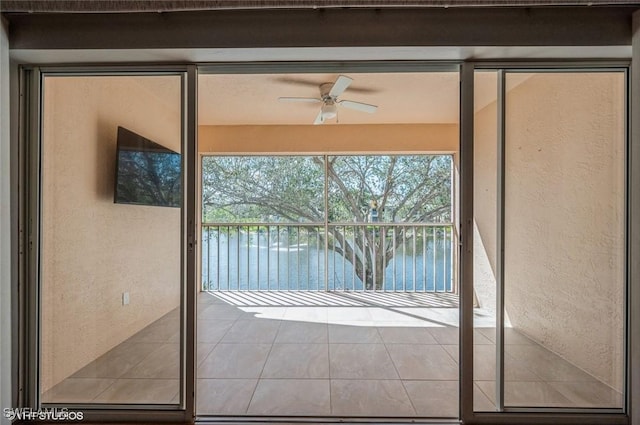 doorway with a water view, a healthy amount of sunlight, ceiling fan, and a textured wall