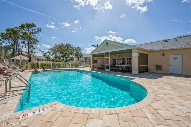 community pool with a patio, fence, and a ceiling fan