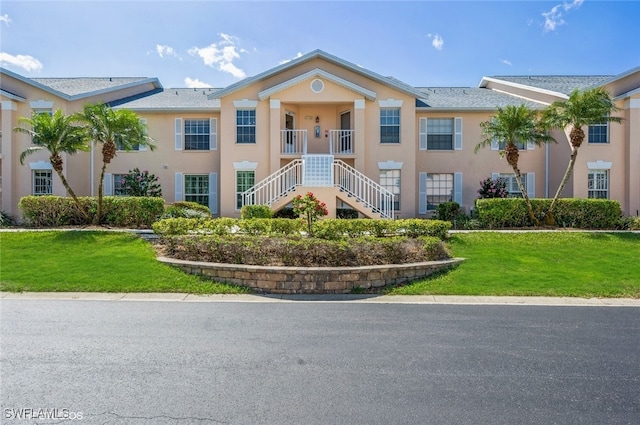 view of front of property with a front yard, stairs, and stucco siding