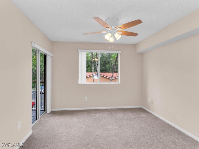 spare room with ceiling fan, a wealth of natural light, a textured ceiling, and carpet floors