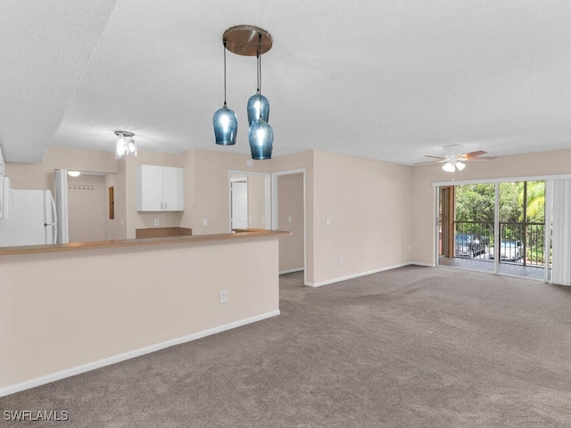 unfurnished living room featuring carpet flooring, ceiling fan, and a textured ceiling