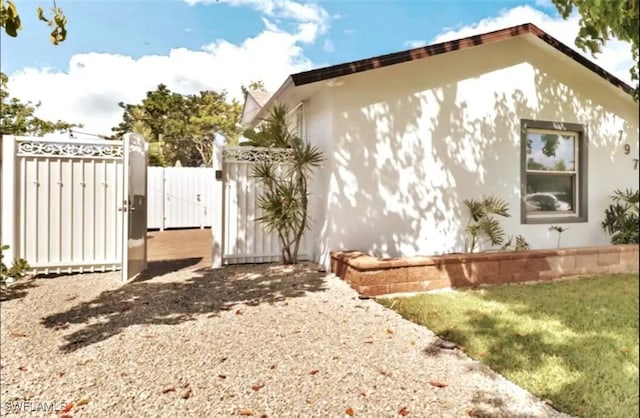 1797 42nd Ter SW, Naples, FL 34116 - view of home's exterior with a gate, stucco siding, and fence