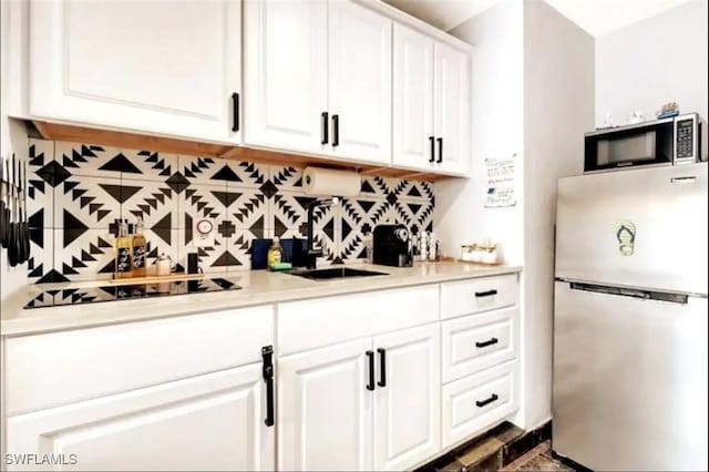 1797 42nd Ter SW, Naples, FL 34116 - kitchen featuring appliances with stainless steel finishes, backsplash, white cabinetry, light countertops, and a sink