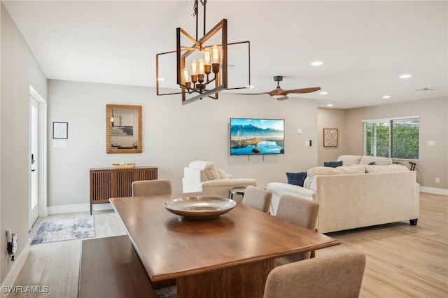 dining room featuring light wood-type flooring and ceiling fan with notable chandelier