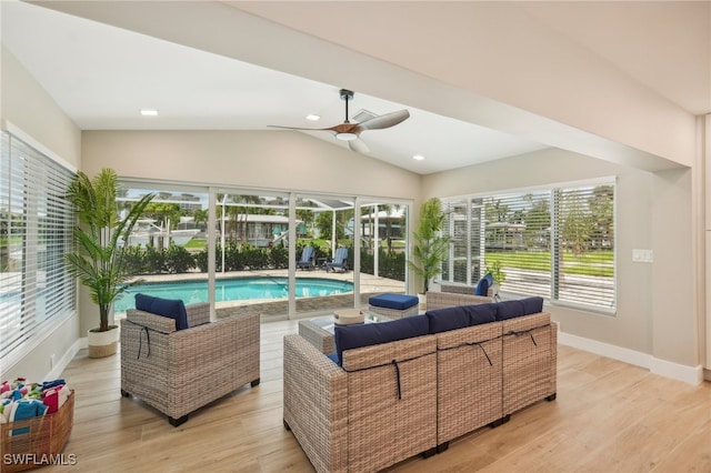 living room with ceiling fan, light hardwood / wood-style floors, and vaulted ceiling