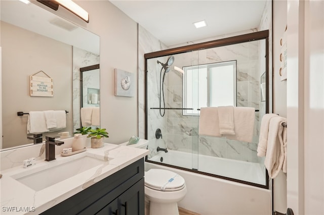 full bathroom featuring combined bath / shower with glass door, vanity, and toilet