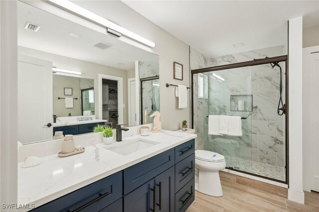 bathroom featuring a shower with door, vanity, toilet, and hardwood / wood-style flooring