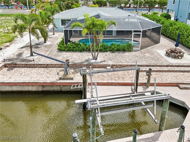 view of dock featuring a lanai, a water view, and a patio