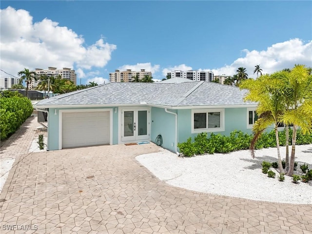 8339 Estero Blvd, Fort Myers Beach, FL 33931 - ranch-style house featuring stucco siding, decorative driveway, french doors, a shingled roof, and a garage