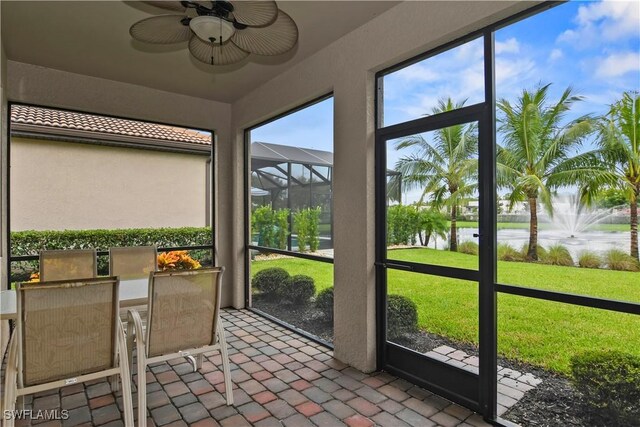 unfurnished sunroom featuring a water view, ceiling fan, and plenty of natural light