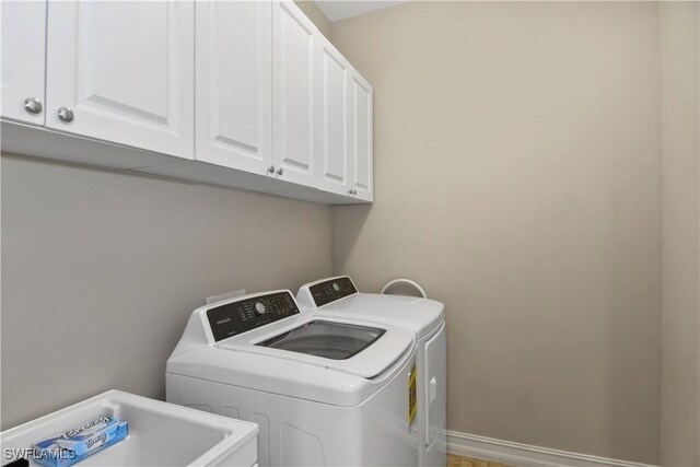 clothes washing area featuring washer and dryer, cabinets, and sink