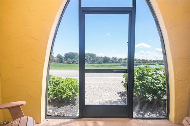 doorway to outside with a water view and concrete floors