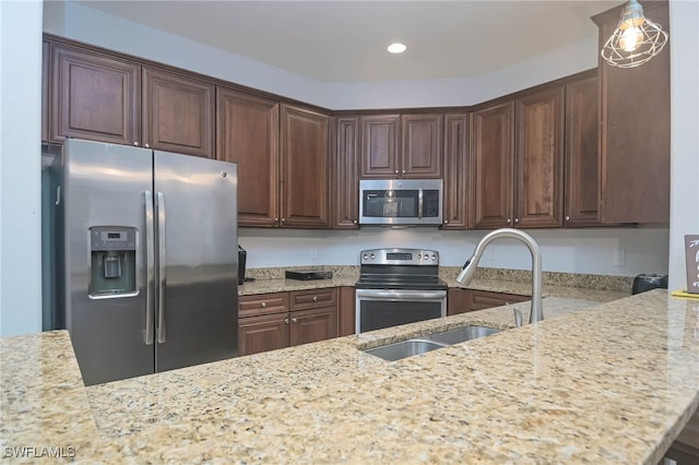 kitchen with dark brown cabinetry, light stone counters, sink, kitchen peninsula, and stainless steel appliances