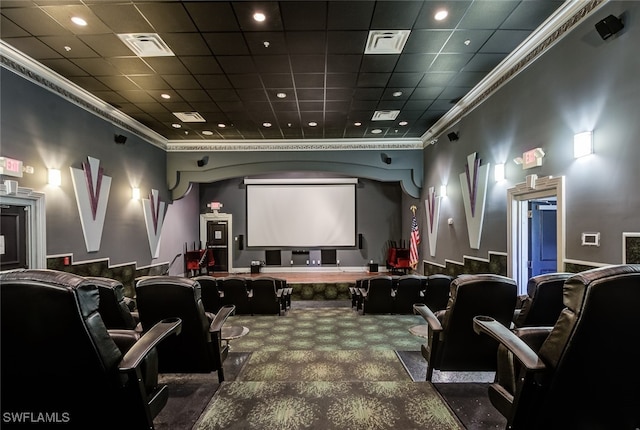 carpeted home theater room with a drop ceiling and ornamental molding