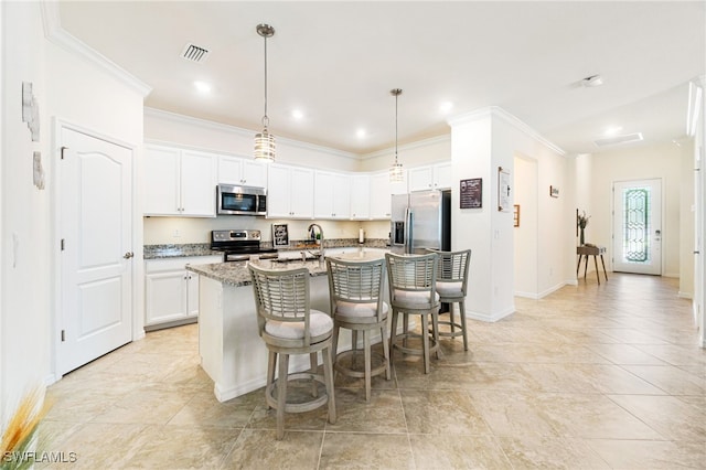 kitchen featuring a center island with sink, visible vents, hanging light fixtures, appliances with stainless steel finishes, and white cabinets