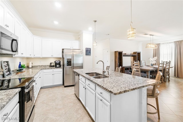 kitchen featuring a kitchen island with sink, stainless steel appliances, a sink, white cabinets, and decorative light fixtures