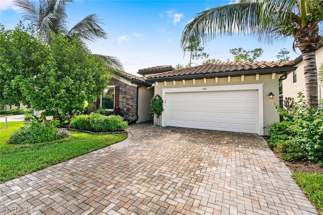 view of front of property with decorative driveway, a tile roof, an attached garage, and stucco siding