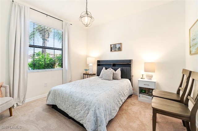 bedroom featuring a chandelier, light carpet, and baseboards