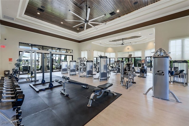 gym with wood ceiling, visible vents, a tray ceiling, and crown molding