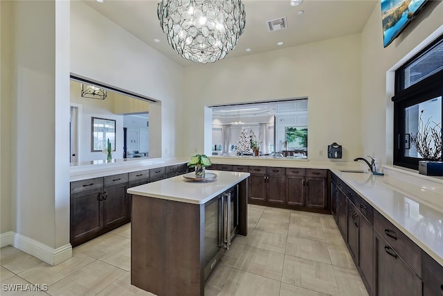 kitchen with a notable chandelier, visible vents, light countertops, a sink, and a peninsula