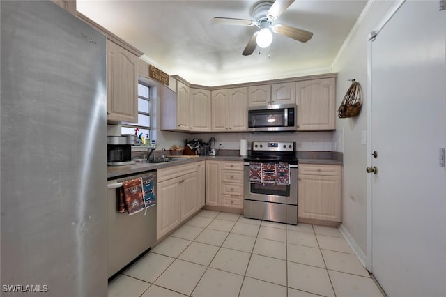 kitchen with light tile patterned floors, stainless steel appliances, light brown cabinetry, and a sink