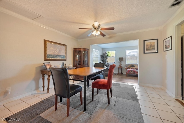 dining room featuring a textured ceiling, ornamental molding, light tile patterned flooring, and visible vents