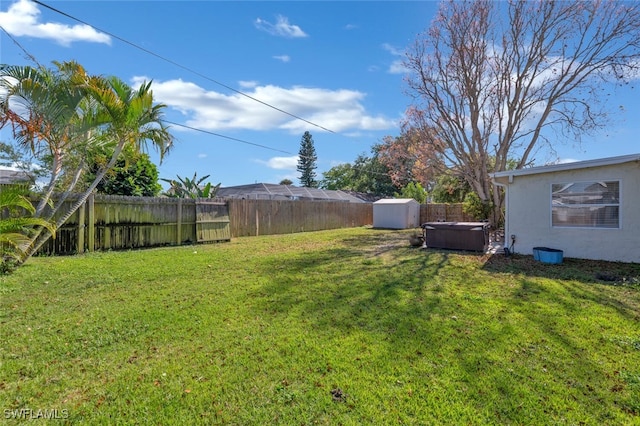 view of yard with a hot tub, a storage unit, a fenced backyard, and an outdoor structure