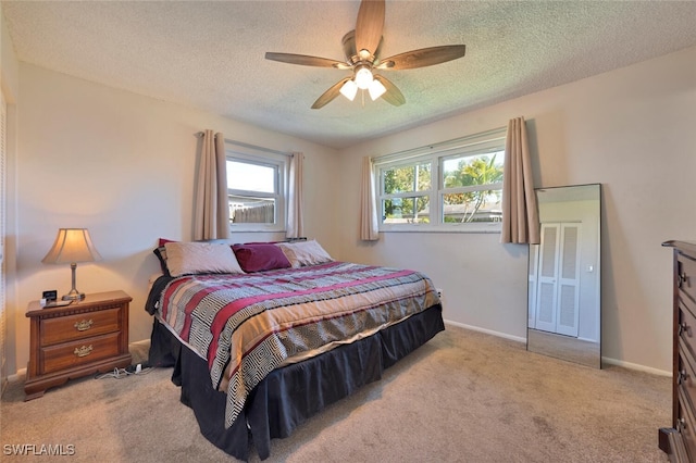 carpeted bedroom featuring a ceiling fan, baseboards, and a textured ceiling