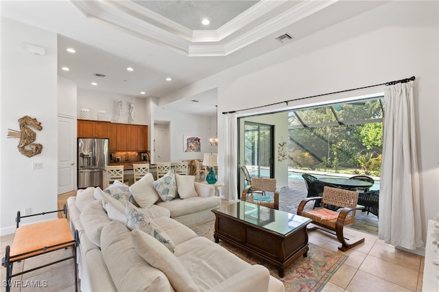 living room with a tray ceiling, ornamental molding, a towering ceiling, and light tile patterned floors