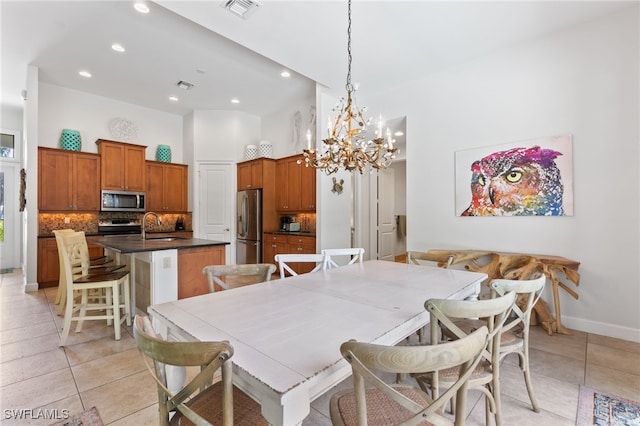 dining space featuring light tile patterned floors, a high ceiling, sink, and a notable chandelier