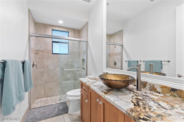 bathroom featuring tile patterned flooring, vanity, toilet, and an enclosed shower